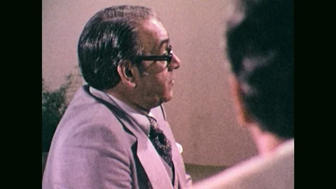 1970s: Man talking, man in foreground, pan to man talking by map. Pointer Stock Footage 102741637