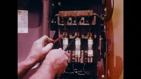 1970s: Man tests circuit breakers in electrical box. Stock Footage