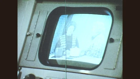 1970s: Man turns knobs by TV monitor, tapes. Men in radio station. DJ motions to Stock Footage 79607100