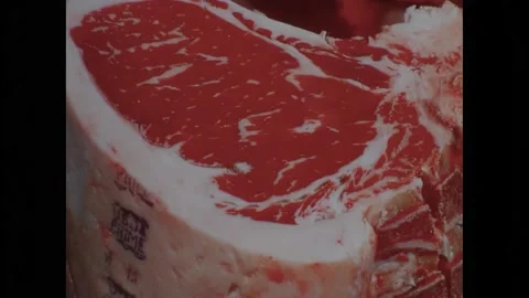 1970s: Man uses tool on side of beef.  Steak.  Logo reads "USDA PRIME."  Butcher Stock Footage 162328265