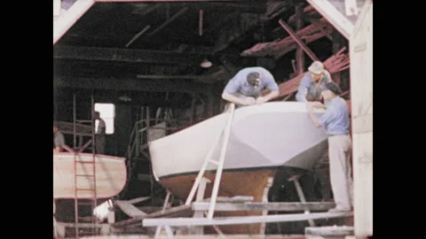 1970s: Men constructing boat. Zoom in, man working on roof. Construction Stock Footage 135201064
