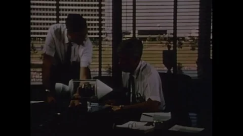 1970s: Men at desk with rocket model / Men consult papers / Men secure suit on Stock Footage 74704456
