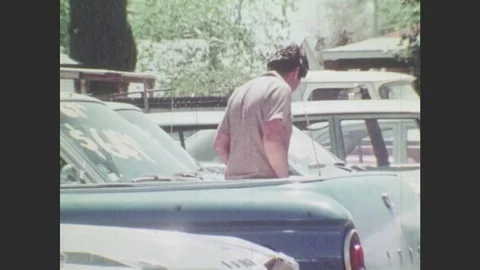 1970s: Men look at used cars. Men walk through lot. Man speaks and gestures. Stock Footage