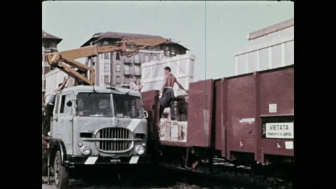 1970s: Men use crane to load train car.  Train rolls down track.  Railyard.  스톡 동영상 134360973