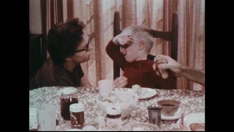 1970s: Mother comforts crying boy at table. Parents rush child to pickup truck Stock Footage 90497558