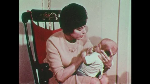 1970s: Mother holds baby in rocking chair, talks to it, cradles its head, rocks Stock Footage