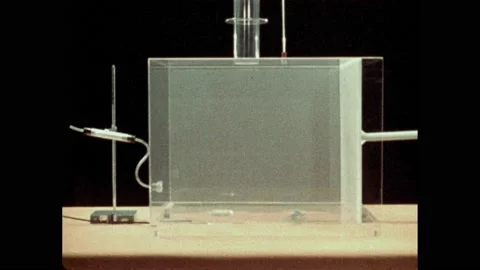 1970s: Plastic shield moving inside box. Hand clamp on hose. Water bubbling in Stock Footage 229567719