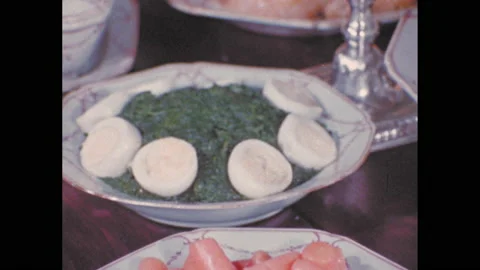 1970s: Plates of carrots, deviled eggs and Cornish game hens on table. Woman Stock Footage 142922659