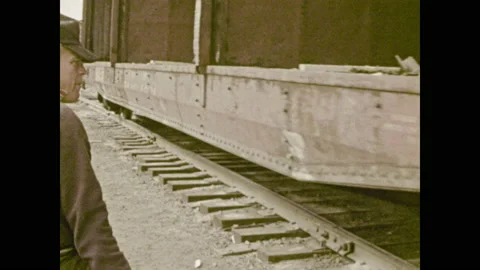 1970s: Rail yard.  Man waves white cloth.  Man pulls lever.  Train moves down Stock Footage 145879320