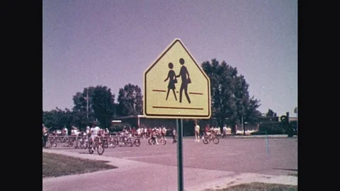 1970s: School crosswalk sign, kids on bikes. School children with books, walking Stock Footage