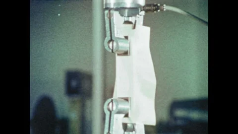 1970s: Scientists test materials, adjust knobs and dials. Man examines suit. Per 스톡 동영상 109216071