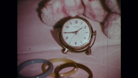 1970s: Small clock on counter. Man talks on phone. Woman tucks child into bed. Vídeos de archivo 121383318