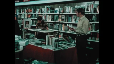 1970s: Split-screen on book and boy in bookshop, zooms in on girl beside him. Stock Footage 258953501