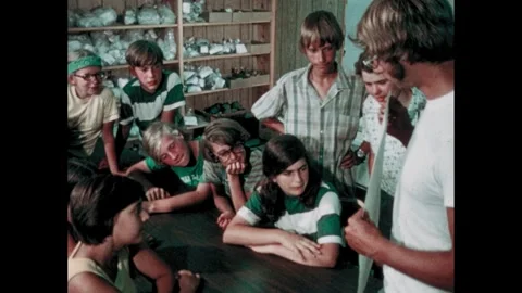 1970s: Students and archaeologist study plot map. Shovel in dirt. Trowel is Vídeos de archivo 284849893