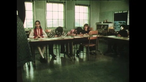 1970s – Students eagerly raise their hands in a classroom as a clown-faced boy Stock Footage 74673049