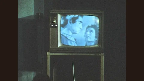 1970s: Students sit in front of TV. Camera crew filming. Man interviews another Stock Footage 79607043