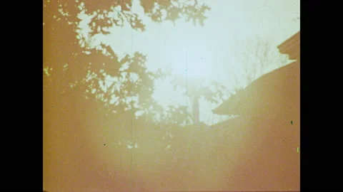1970s: The sun shines behind trees. Birds sing. Suburban neighborhood street. Stock Footage 135206881