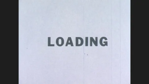 1970s: Text frame says LOADING.  Men in hard hats walk along razed area near Stock Footage 78012912