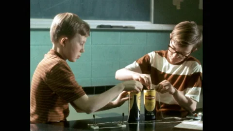1970s: Two boys attach two batteries to a parallel circuit, consisting of Video stock 163452910