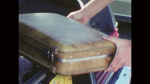 1970s: Uniformed man opens suitcase and looks in suitcase, closes and latches Stock Footage 77219824