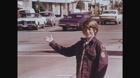 1970s: UNITED STATES: boy hitches lift on road. Boy talks to man in car. Stock Footage