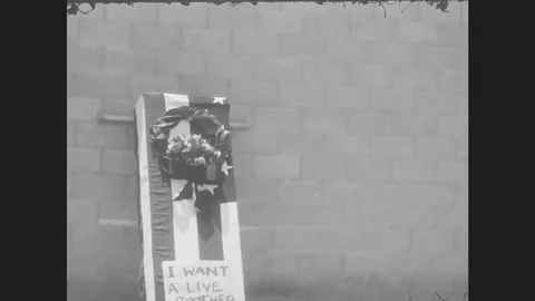 1970s: UNITED STATES: coffin by wall. 'I want a live brother' sign. Man and lady Stock Footage