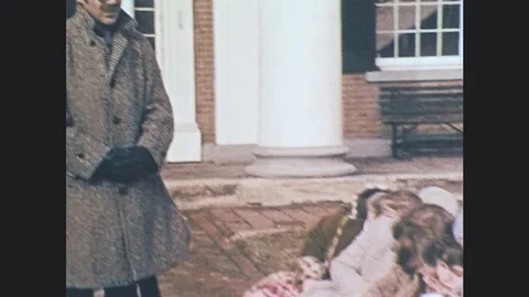 1970s: UNITED STATES: man speaks by building. Children sleep on bench. Cartoon Stock Footage