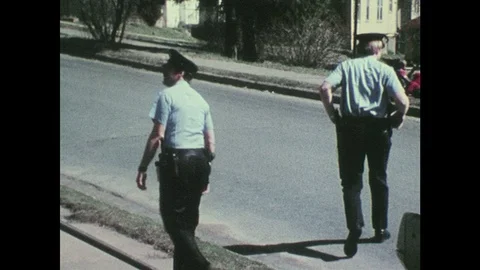 1970s: UNITED STATES: Officers leave scene of domestic incident. Police man gets Stock Footage