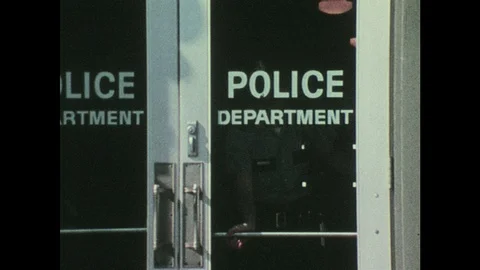 1970s: UNITED STATES: Police Officers walk out of Police Department doors. Man Stock Footage