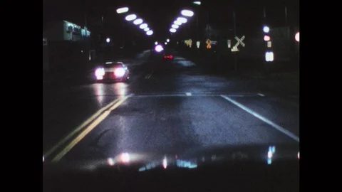 1970s: UNITED STATES: side view as man drives car at night. View of mountains Stock Footage 77432656