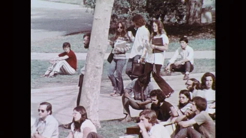 1970s: UNITED STATES: students walk through university campus. Students sit on Stock Footage