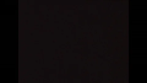 1970s: View of driver from backseat of car. Car parked on side of street. Driver Stock Footage