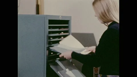 1970s: Woman grabs multiple documents at once as they come out of printer in Stock Footage 157935519