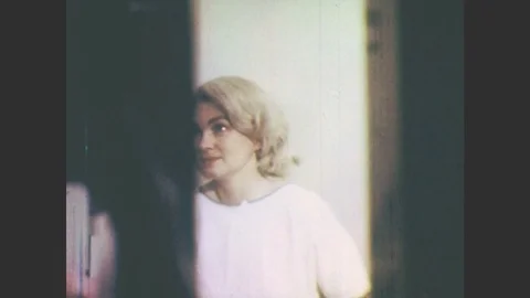 1970s: Woman in hospital gown stands up before nurse. Man hooked up to breathing Stock Footage