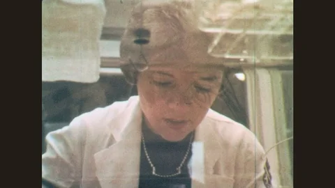 1970s: Woman looks into isolette. Baby wearing headgear for test. Woman turns Stock Footage