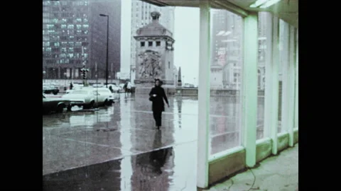 1970s: Woman walks across building courtyard in rain then enter door of Bank. Stock Footage