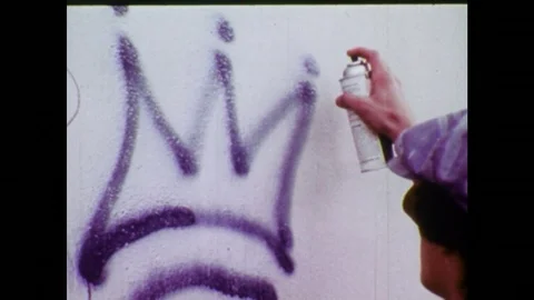 1970s: Young man graffitis a wall then runs away. Title of film shows, “Graffiti Stock-Footage 75173139