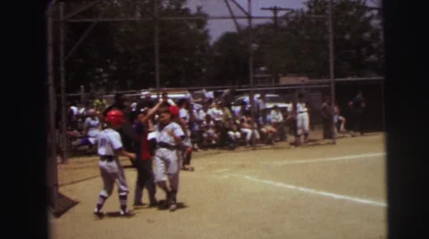 1972: An Older Boy in Gray Baseball Uniform and Red Batters Cap at Bat Stock Footage 67614231