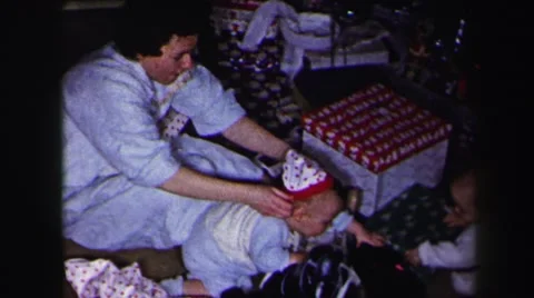 1972: parents putting matching stocking caps on kids xmas tree patterned Stock Footage