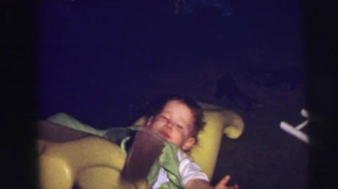 1973: baby falling over playing on yellow banana rocking chair LYNBROOK Stock Footage