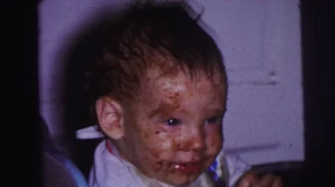 1973: birthday party cake covered baby smiles eating frosting LYNBROOK, NEW YORK Stock Footage