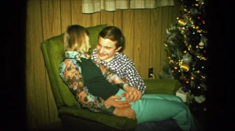 1974: couple is sitting next to christmas tree FORT WAYNE, INDIANA Stock Footage