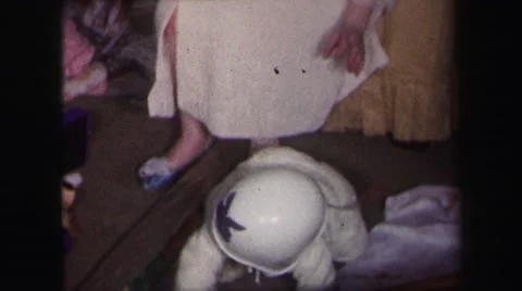 1974: a woman adjust a helmet on top of a baby's head as it crawls around. Stock Footage