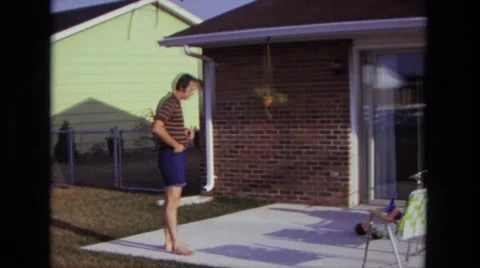 1975: man summertime backyard porch area lighting up cigarette CALIFORNIA Stock Footage