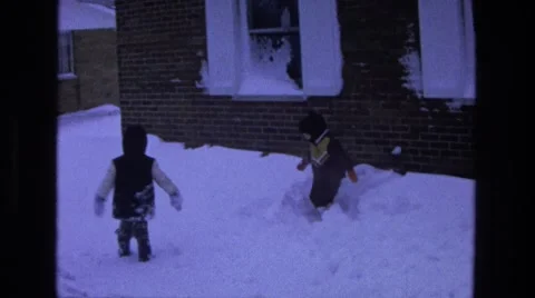 1975: two children bundled in winter clothes trudge through snow Stock Footage