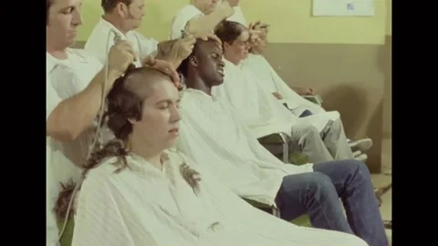 1980 - Barbers give buzz cuts to black and white recruits at Lackland Air Force Stock Footage 241809360