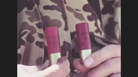 1980s: Hands hold shotgun shells. Flock of birds flying, zoom out. 動画素材 76847581