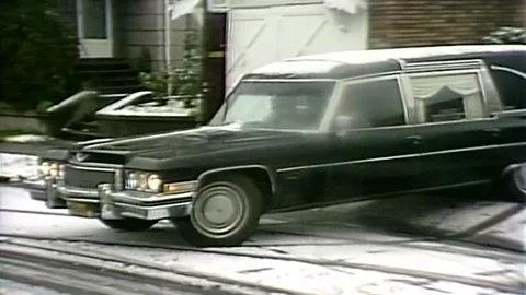 1980S HEARSE WITH COFFIN PULLING OUT ONTO SNOW COVERED ROAD Stock Footage 250146922