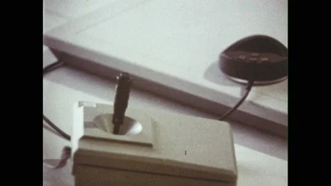 1980s: Joystick sits next to computer keyboard. Man moves mouse on large pad and Video stock 226412166