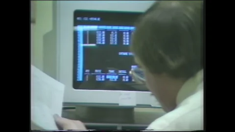 1980s: man at computer writing and reading information on screen and checking it Stock Footage 129852986